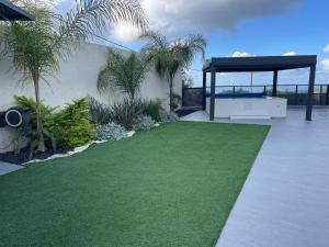 a backyard with a green lawn and a gazebo at אחוזת שקד בוטיק - מתחם פרטי 3 חדרי שינה, בריכה מחוממת , ג'קוזי ונוף בגליל המערבי in ‘Ein Ya‘aqov