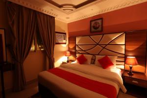a hotel room with a large bed with red pillows at Jubail Rose in Al Jubail