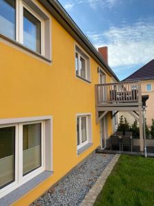 una casa amarilla con una terraza en el costado. en Hempis Ferienwohnungen, en Hochkirch