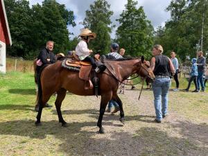 una niñita sentada en un caballo con un grupo de gente en EddyLou Ranch en Slöinge