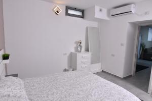 a white bedroom with a bed and a dresser at Deluxe Basement Apartment Bahai's Garden in Haifa