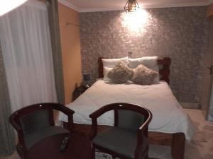 een slaapkamer met een bed met twee stoelen erin bij Sparkle Residency in Nairobi
