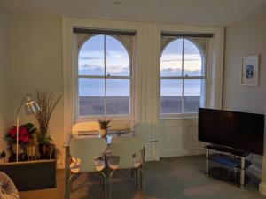 a living room with three windows and a table and chairs at 3BD Coastal Retreat with Spectacular Sea Views in Folkestone