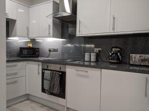 a kitchen with white cabinets and a microwave at 3BD Coastal Retreat with Spectacular Sea Views in Folkestone