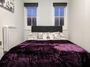 a bedroom with a purple bed with two windows at 3BD Coastal Retreat with Spectacular Sea Views in Folkestone