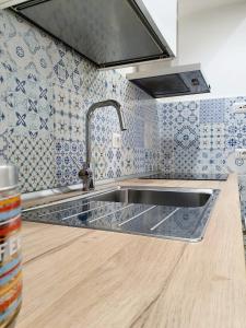 een roestvrijstalen wastafel in een keuken met blauwe en witte tegels bij Colibrì a Piazza Dante in Napels