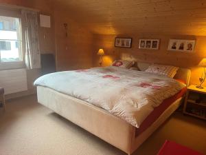 a bedroom with a large bed in a wooden room at Gäuggeliweg 36, Klosters in Klosters