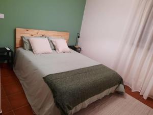 una camera da letto con un grande letto bianco con cuscini rosa di Casa da Dina a Ponte de Lima