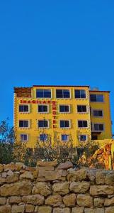 un edificio giallo dietro un muro di pietra di fronte a un edificio di Shaqilath Hotel a Wadi Musa