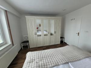 a bedroom with a bed and a large white cabinet at Apartman Studenac in Kiseljak