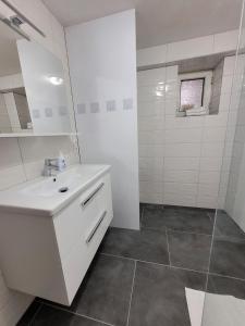 a white bathroom with a sink and a shower at Apartman Studenac in Kiseljak