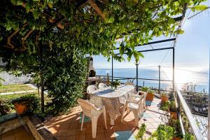 una mesa y sillas en un balcón con vistas al océano en Torre di Amalfi - holiday house, en Amalfi