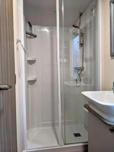 a shower with a glass door next to a sink at Modern 2 Bedroom Mobile home with parking on St Helens Coastal Resort Isle of Wight in Saint Helens