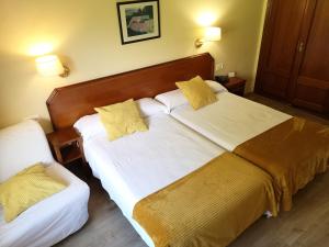 Cette chambre d'hôtel comprend 2 lits avec des oreillers jaunes. dans l'établissement Hotel y Casona El Carmen, à Perlora