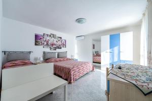 a white bedroom with two beds and a table at Torre di Amalfi - holiday house in Amalfi