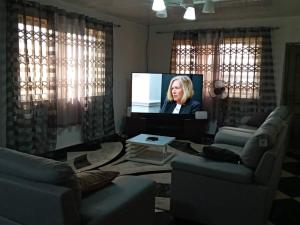 una sala de estar con TV con una mujer. en Well presented apartment with 2 master bedrooms. en Freetown