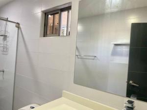 Baño blanco con espejo y lavabo en Apartamento en el epicentro del Carnaval, en Barranquilla