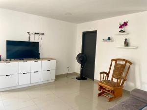 a living room with a tv and a chair at Apartamento en el epicentro del Carnaval in Barranquilla