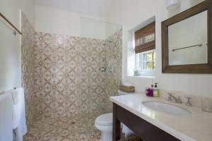 a bathroom with a sink and a toilet and a mirror at Buccaneer Hill Cottage cottage in Governorʼs Harbour