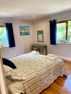 a bedroom with a large bed with blue curtains at Beautiful Riverside Retreat in Blackwater, Wexford in Blackwater