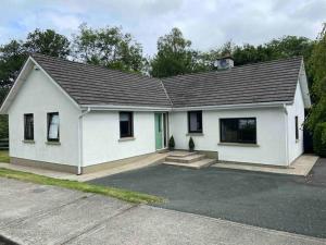 a small white house with a driveway at Beautiful Riverside Retreat in Blackwater, Wexford in Blackwater