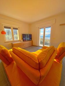 Un gran sofá naranja en una sala de estar con ventanas. en Cochetto's House in Malcesine, en Malcesine