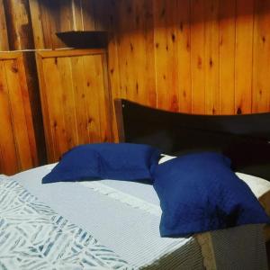 a bed with blue pillows on top of it at Sítio Bona Vita in Nova Trento