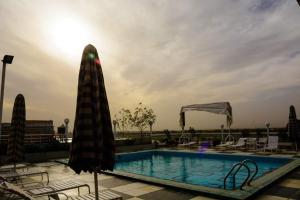 a swimming pool with an umbrella and chairs and tables at New Pola Hotel in Luxor