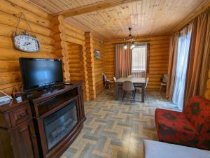 a living room with a television and a dining table at LOG HOUSE in Bakuriani