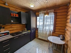 巴庫里阿尼的住宿－LOG HOUSE，厨房配有桌子、炉灶和窗户。