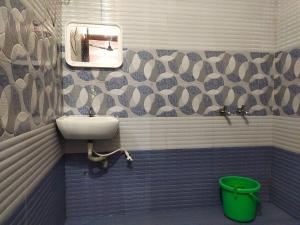 a bathroom with a sink and a mirror and a bucket at KATAKERI HOLIDAY HOME in Madikeri