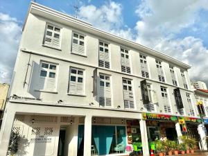 a white building with white shutters on a street at The Assembly Place, Hotel at Veerasamy in Singapore