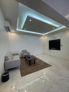 قمم بارك 3 Qimam Park Hotel في أبها: غرفة معيشة مع أريكة وتلفزيون على الحائط