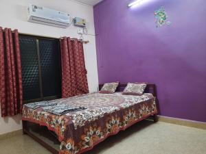 Omkar Beach Resort في مالفان: غرفة نوم بجدران أرجوانية وسرير بمخدات