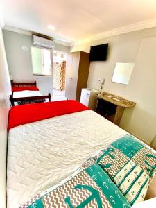 a bedroom with a large bed with a red blanket at Loft e Suites Temporada in Balneário Camboriú