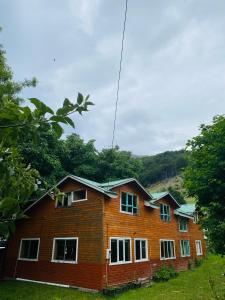 Casa de madera con ventanas blancas y árboles en Turismo Rural Los Alpes, en Futaleufú