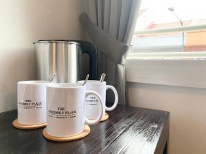 three coffee mugs sitting on a table next to a window at The Assembly Place, Hotel at Veerasamy in Singapore