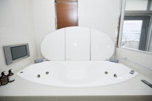 y baño con bañera blanca y espejo. en スタンザベルデ名古屋 en Nagoya