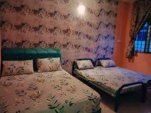 a bedroom with two beds in a room with purple walls at D'Diana Homestay in Port Dickson