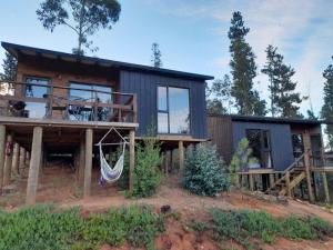 una cabaña de madera con una hamaca frente a ella en Cabañas Wildki Lodge Vichuquen, en Curicó