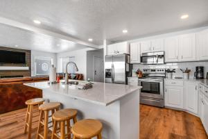 uma cozinha com armários brancos e uma ilha de cozinha com bancos em Harbor Village Retreat em Garden City