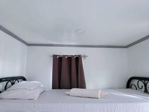 1 dormitorio con cama blanca y cortina marrón en 4 - Affordable 2-Storey House in Cabanatuan City, en Cabanatúan