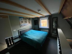 um quarto com uma cama azul e uma janela em Appartement - B&B de Koog em Uitgeest