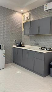 uma cozinha com armários brancos, um lavatório e um frigorífico em قمم بارك 3 Qimam Park Hotel em Abha