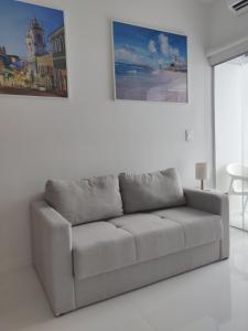 un sofá en una habitación blanca con una pintura en la pared en Bahia Flat Apt 107, en Salvador