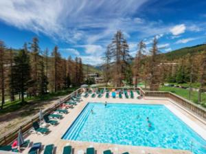 una piscina con sillas y gente en ella en Résidence L’Albane, en Vars