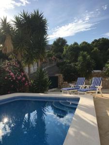 - deux chaises bleues et blanches à côté de la piscine dans l'établissement Villa França Air conditioned villa with sea view, WiFi, and private pool, à Alcossebre