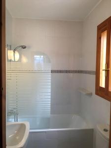 La salle de bains blanche est pourvue d'une baignoire et d'un lavabo. dans l'établissement Villa França Air conditioned villa with sea view, WiFi, and private pool, à Alcossebre