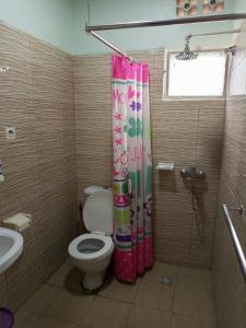 a bathroom with a toilet and a shower curtain at Puma Garden and Suites - Nyarutarama in Kigali