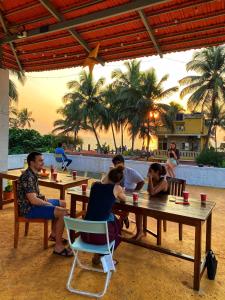 a group of people sitting at tables on the beach at Hostel Mandala in Anjuna